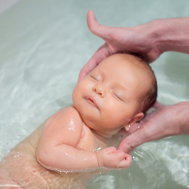 Newborn,Baby,Swimming,With,Help,Of,Parents,Hands,For,The